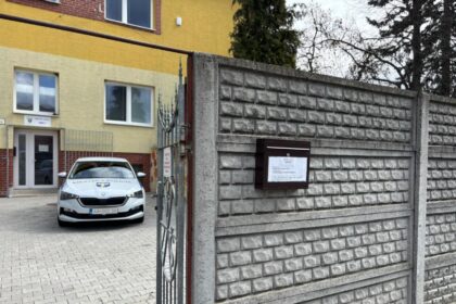 Brána s nápisom Mestská polícia a policajné auto zaparkované pred budovou mestskej polície v Gbeloch.