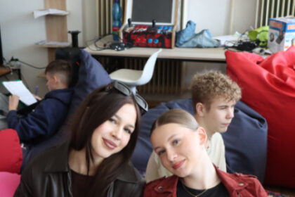 Dve ženy sediace na vankúšoch počas diskusie v mládežníckej klubovni KiviK, v pozadí ďalší mladí ľudia.