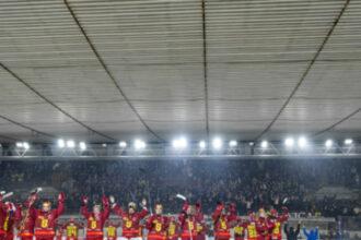 Hokejový tím HC Dukla Senica v červeno-žltých dresoch oslavuje víťazstvo na ľade pred početným publikom.