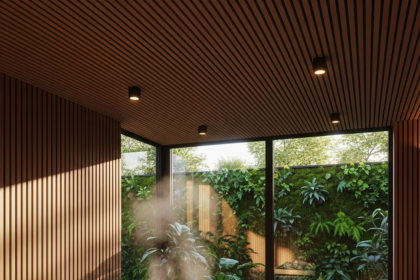 Interiér sauny v Holíči s drevenými stenami, veľkými oknami a stolom s kameňmi a parou, obklopený rastlinami a drevenými lavicami.