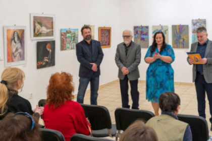 Ľudia na vernisáži výtvarnej súťaže Výtvarná Senica 2026 v galérii pred vystavenými obrazmi.