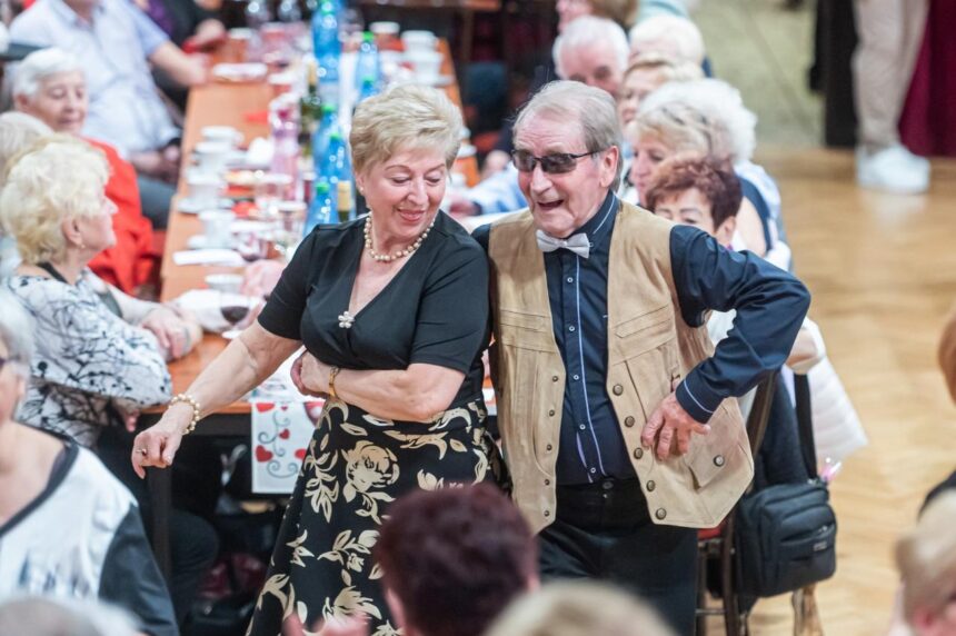 Muž a žena tancujúci na podujatí Medzinárodného dňa žien v Skalici, v pozadí ďalší účastníci pri stole.