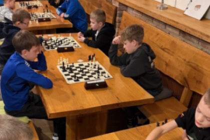 Skupina detí hrá šach pri stoloch na mládežníckom šachovom turnaji GPX na Kolibe v Senici.