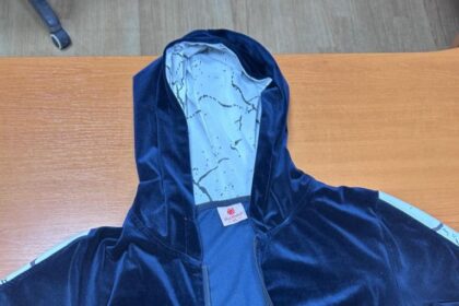 Tmavomodrá mikina s bielymi pásmi na rukávoch položená na povrchu.