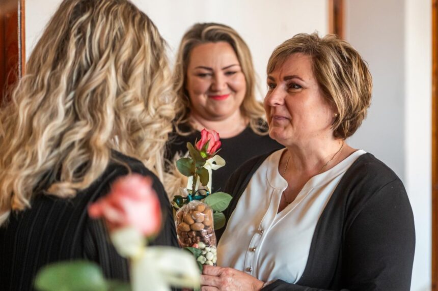 Ženy na slávnostnom oceňovaní sociálnych pracovníkov v Skalici, jedna drží kyticu s ružou a sladkosťami.