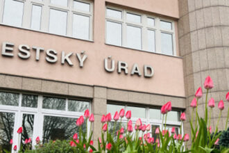 Budova Mestského úradu v Senici s ružovými tulipánmi v popredí počas jarného dňa.