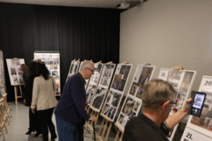 Ľudia si prezerajú výstavu s panelmi fotografií v Múzeu Senica počas premiéry dokumentárneho filmu o Jánovi Hromkovi.