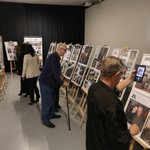 Ľudia si prezerajú výstavu s panelmi fotografií v Múzeu Senica počas premiéry dokumentárneho filmu o Jánovi Hromkovi.