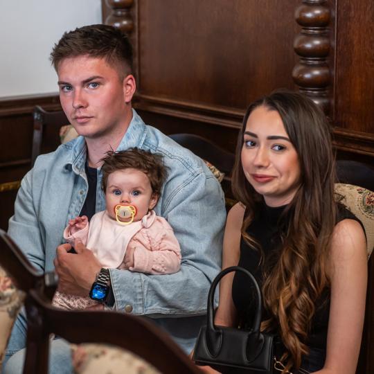 Mladí rodičia sediaci s dieťaťom v obradnej miestnosti Mestského úradu v Skalici počas slávnostného privítania najmladších občiankov mesta.