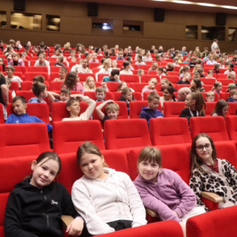 Skupina dievčat sedí na červenej sedačke v sále počas eko-muzikálu v Senici, v pozadí sú ďalší diváci.