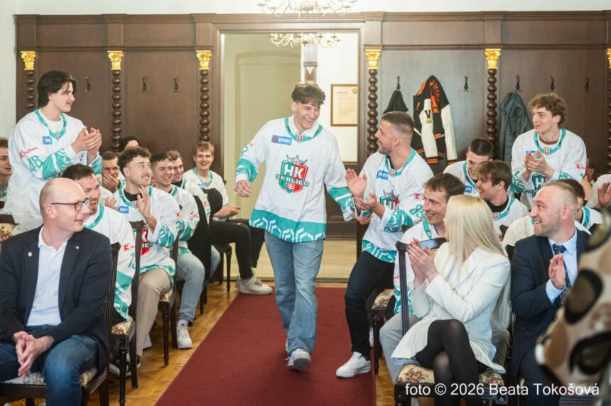 Skupina hokejistov HK Skalica v drese na slávnostnom prijatí v radnici mesta Skalica, niektorí tlieskajú a usmievajú sa.