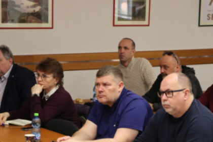 Skupina starostov a starostiek okresu Senica sediacich pri stole počas pracovného stretnutia, diskutujúcich o bezpečnosti a sociálnych službách.