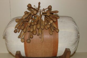 Vankúš na paličkovanie s množstvom paličiek, ktoré sú rozmiestnené na vrchu, ilustrujúci tradičné remeslo v Záhorskom múzeu Skalica.