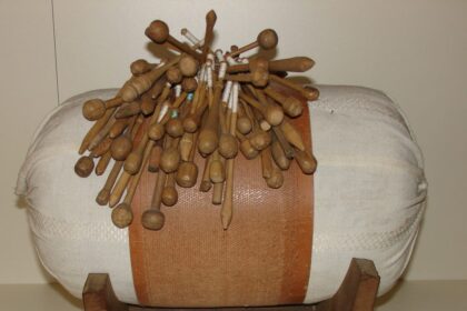 Vankúš na paličkovanie s množstvom paličiek, ktoré sú rozmiestnené na vrchu, ilustrujúci tradičné remeslo v Záhorskom múzeu Skalica.