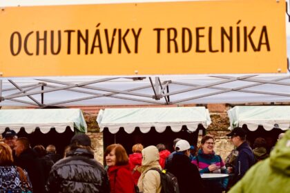 Návštevníci ochutnávajú trdelníky na Trdlofeste v Skalici, vidieť stánky a ľudí pri podujatí.