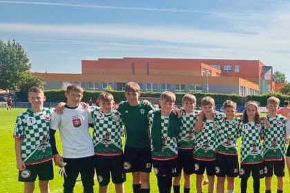 Skupina mladých futbalistov zo Skalice v čierno-bielych dresoch na futbalovom ihrisku počas turnaja.