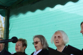 Skupina spevákov zo speváckeho zboru Seniorka spievajúcich na pódiu počas kultúrneho programu na Námestí oslobodenia v Senici.