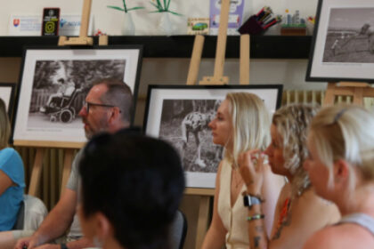 Skupina pedagógov sediacich v miestnosti počas vitalizačného workshopu v Senici, na stenách sú fotografie.