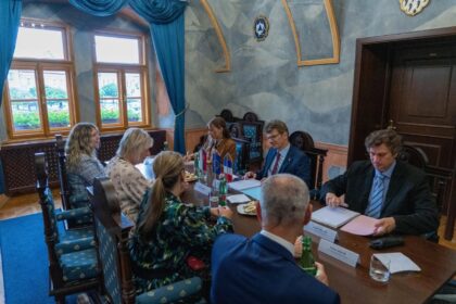 Stretnutie ôsmich osôb pri stole v konferenčnej miestnosti počas oficiálnej návštevy francúzskeho veľvyslanca v Skalice.