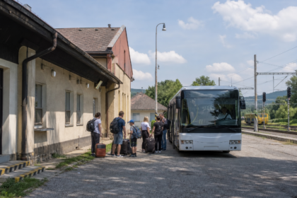Autobus pri malej železničnej stanici a čakajúci cestujúci.