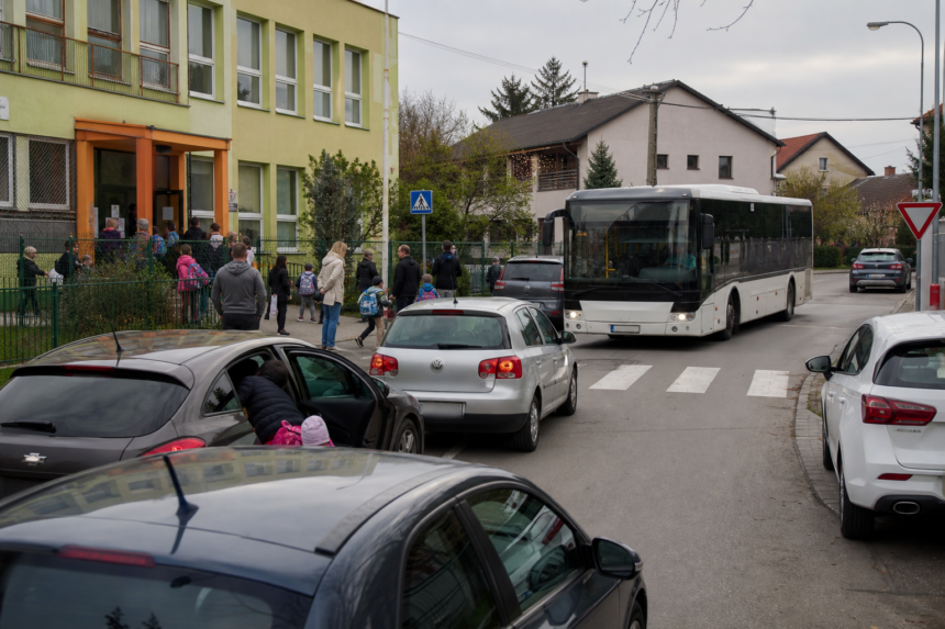 Ranná dopravná situácia pri škole v Senici s autami a prechádzajúcim autobusom.