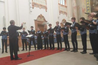Spevácky zbor vystupuje v interiéri kostola pred publikom.