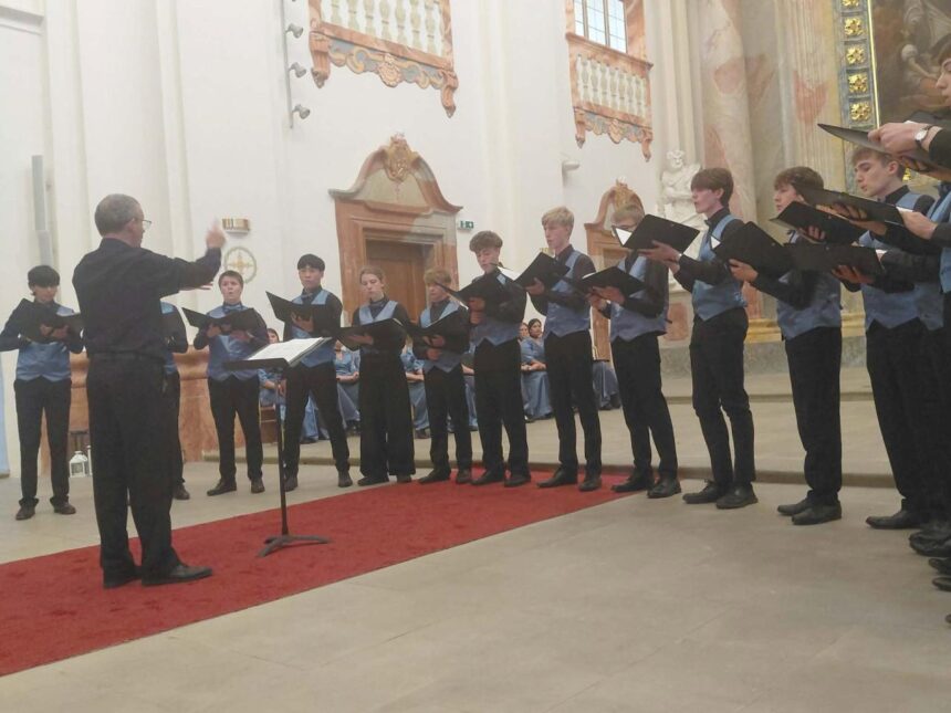 Spevácky zbor vystupuje v interiéri kostola pred publikom.