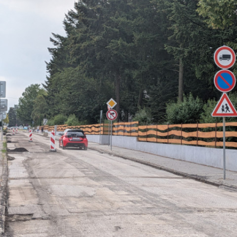 Cestná komunikácia v rekonštrukcii s dopravným značením a osobným autom