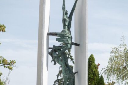 Pamätník s vencami a dvoma uniformovanými osobami pri pietnom akte v Skalici.