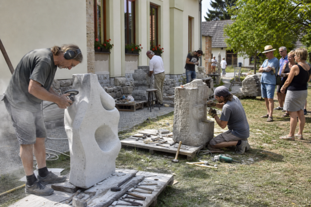 Sochári pracujú na kamenných plastikách počas vonkajšieho sympózia.