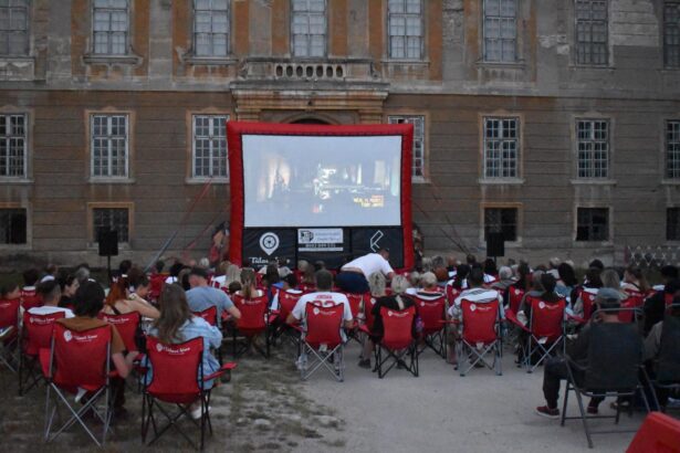 Vonkajšie filmové premietanie pred historickou budovou s publikom na stoličkách a veľkým plátnom.