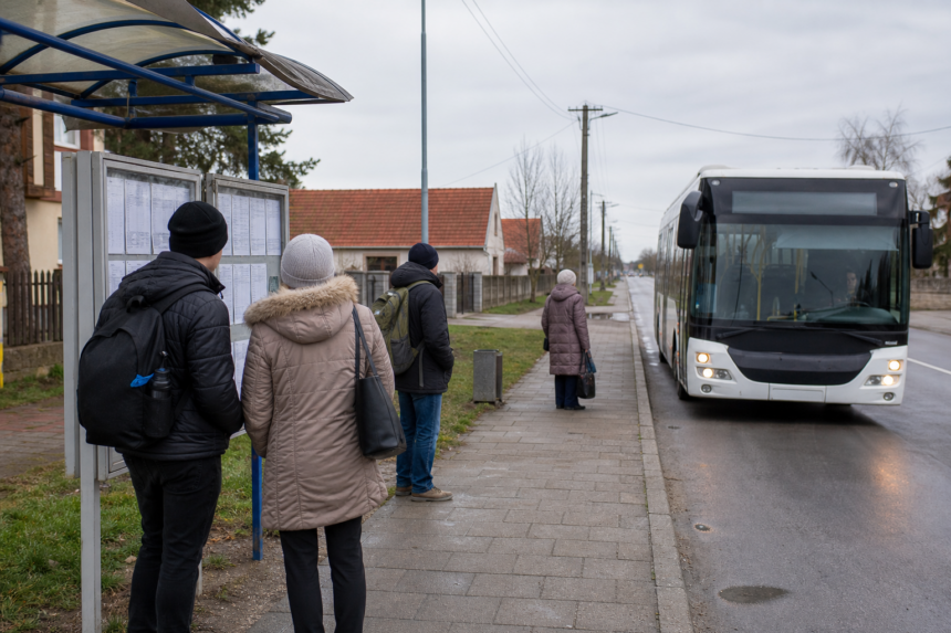 Autobusová zastávka v západnom Slovensku s cestujúcimi pri cestovnom poriadku