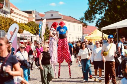 Dav ľudí na skalickom námestí počas jarmoku, pri stánkoch a dvoch osobách na chodúľoch.