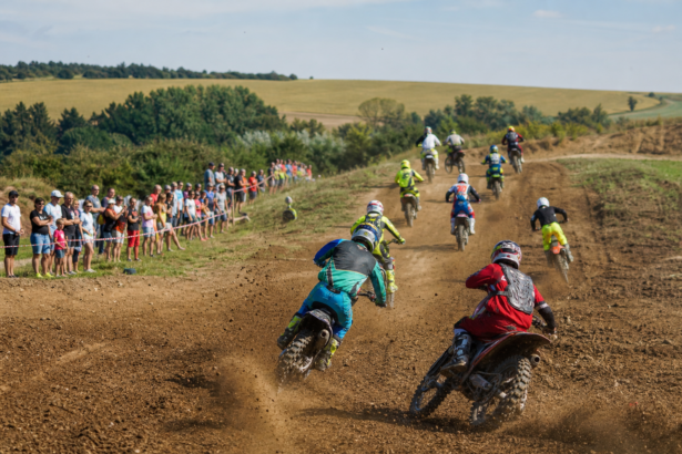 Motokrosoví jazdci na prašnej trati pred divákmi.