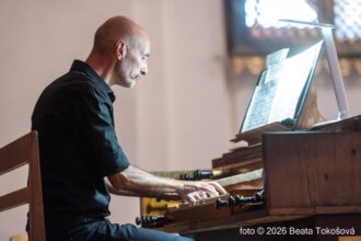 Organista hrá na organe v interiéri kostola.