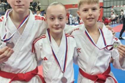 Tri deti v karate kimone s medailami.
