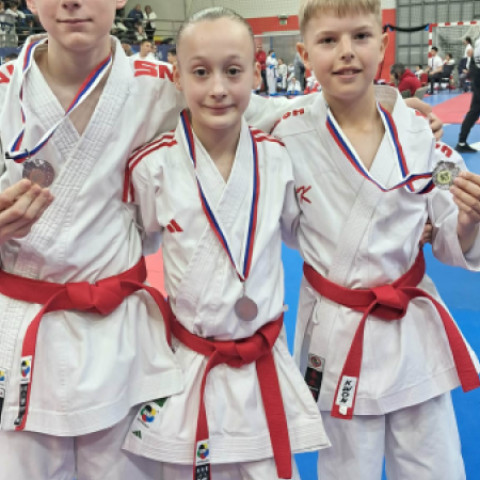 Tri deti v karate kimone s medailami.