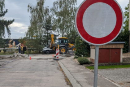 Zákazová dopravná značka pri ceste v rekonštrukcii so stavebnými strojmi v pozadí.