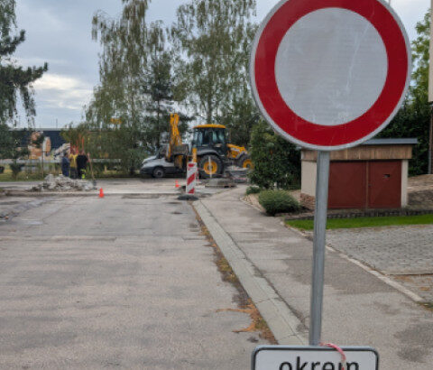 Zákazová dopravná značka pri ceste v rekonštrukcii so stavebnými strojmi v pozadí.