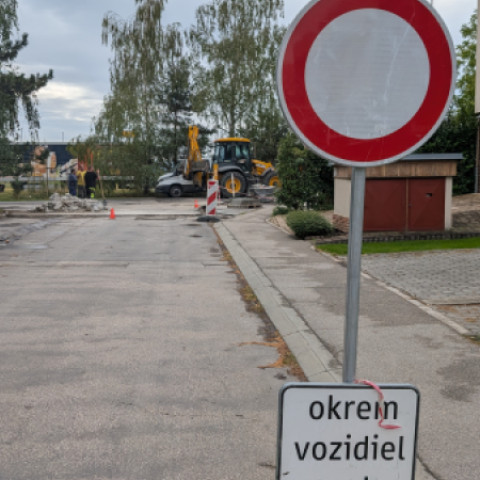 Zákazová dopravná značka pri ceste v rekonštrukcii so stavebnými strojmi v pozadí.