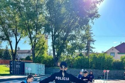 Deti na dopravnom ihrisku s policajtom počas výučby pravidiel cestnej premávky.