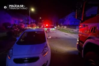 Nočná dopravná nehoda na ceste s policajnými a hasičskými vozidlami so zapnutými majákmi.
