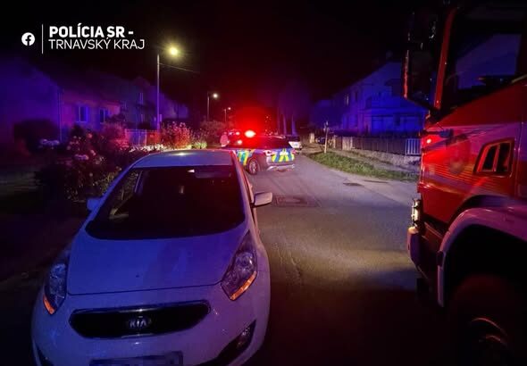 Nočná dopravná nehoda na ceste s policajnými a hasičskými vozidlami so zapnutými majákmi.