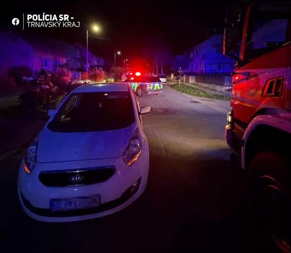 Nočná dopravná nehoda na ceste s policajnými a hasičskými vozidlami so zapnutými majákmi.
