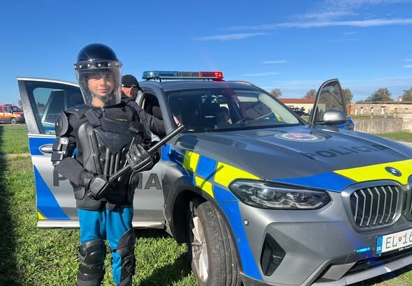 Policajt pri policajnom vozidle počas ukážky pre deti.