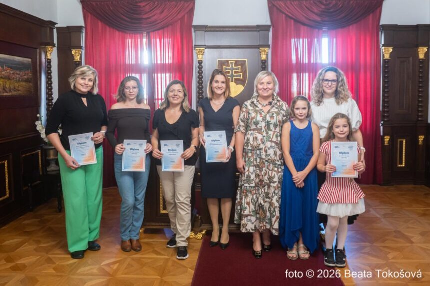 Skupina ľudí pri odovzdávaní diplomov v interiéri