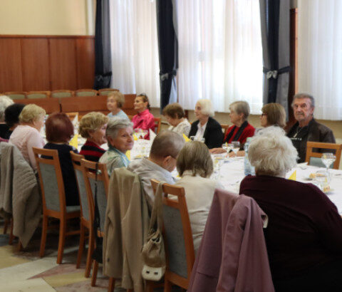 Spoločenské posedenie seniorov pri prestretom stole v sále