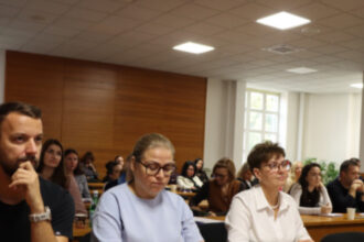 Účastníci seminára sedia v zasadačke pri stole s notebookom a poznámkami.