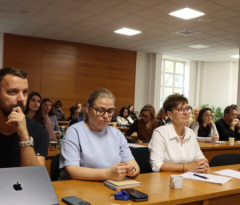 Účastníci seminára sedia v zasadačke pri stole s notebookom a poznámkami.